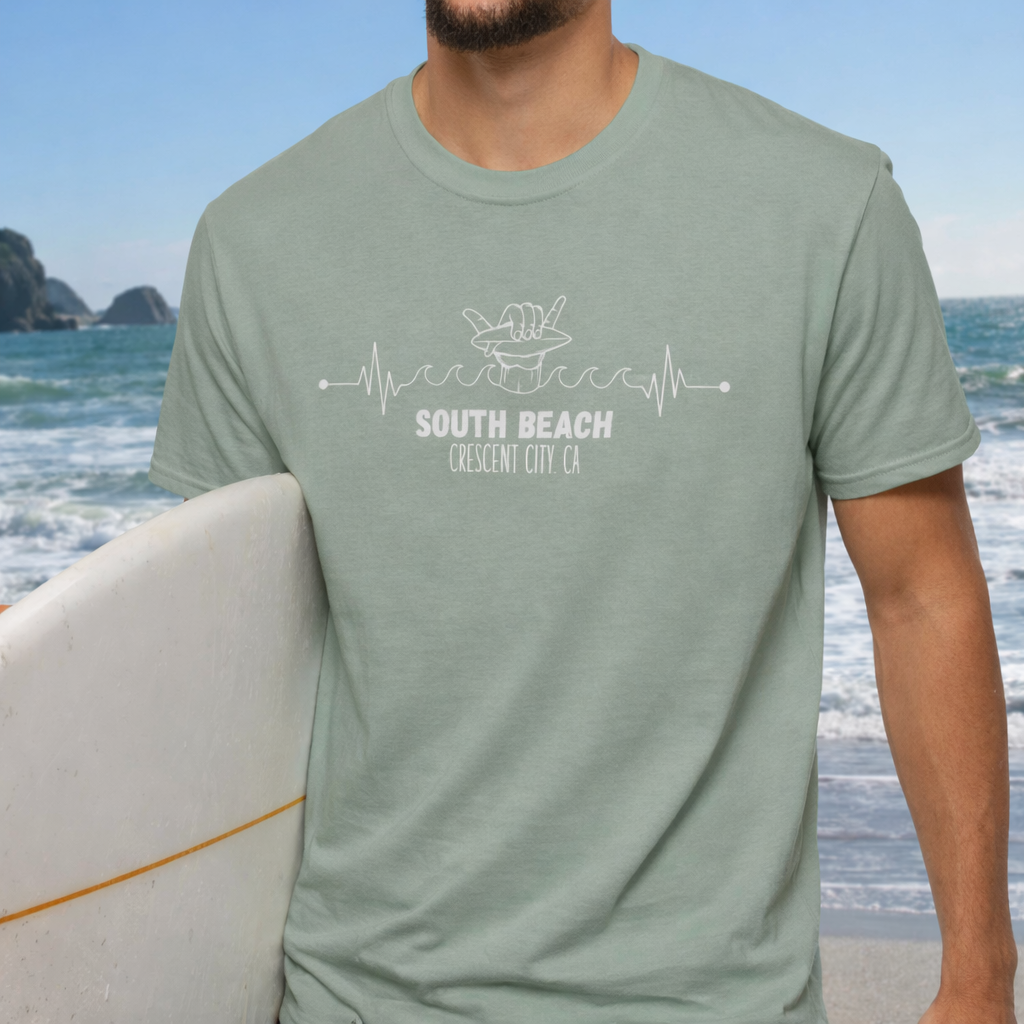 Person wearing a green t-shirt with 'South Beach Crescent City CA' hang ten surf design on a beach.