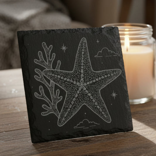 Black slate coaster with starfish and coral engraving.