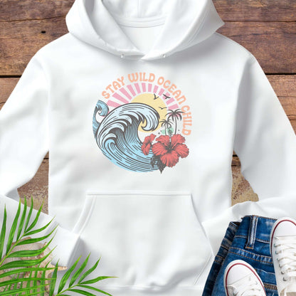 White hoodie with retro beach artwork featuring a stylized wave, palm trees, hibiscus flowers, and the phrase "Stay Wild Ocean Child" in sunset colors.