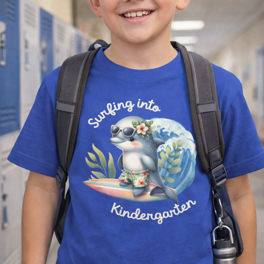 Child wearing a blue t-shirt with a dolphin graphic and text Surfing into Kindergarten.