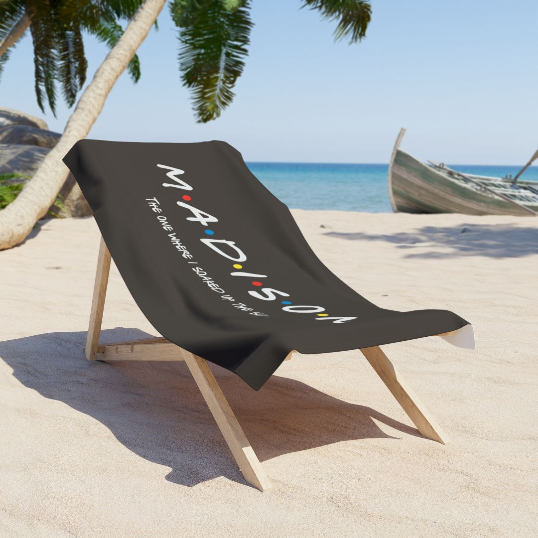 Black beach towel with personalized dotted name and the phrase “The One Where I Soaked Up the Sun!”