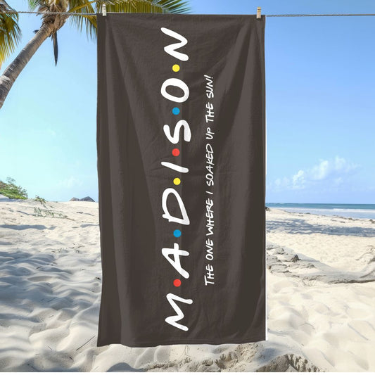 Black beach towel with personalized dotted name and the phrase “The One Where I Soaked Up the Sun!”