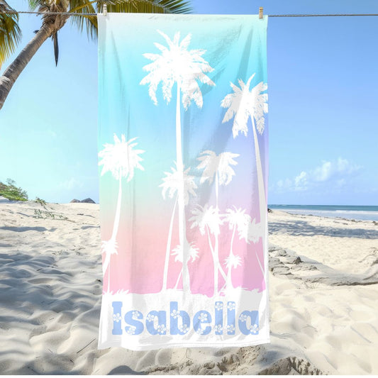 Personalized beach towel with blue-to-pink gradient, palm trees, and custom name at the bottom