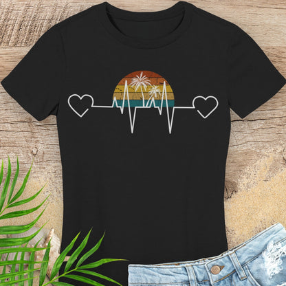 Black t-shirt with a heart rate design featuring palm trees and a sunset on a wooden surface.