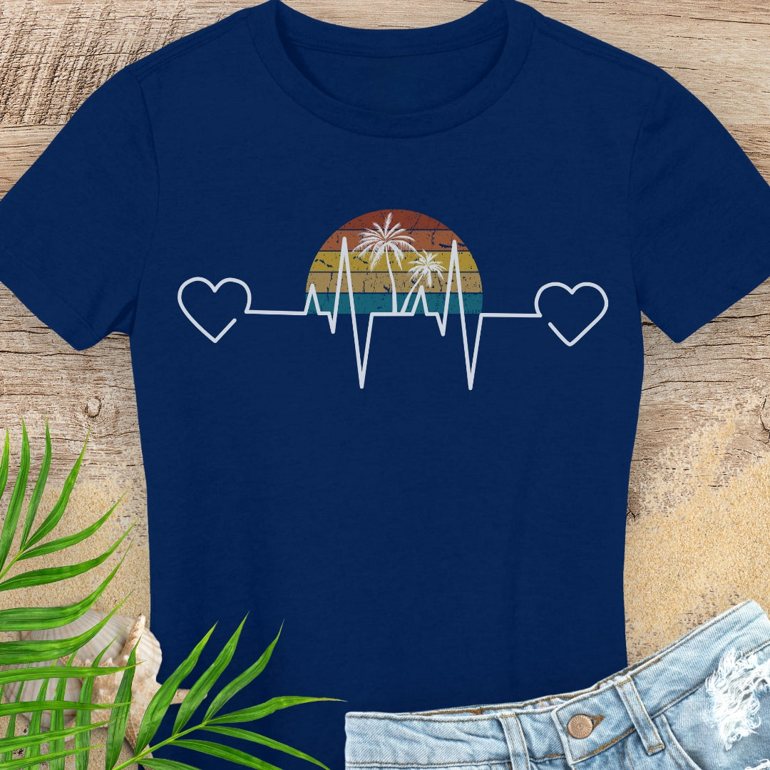 Navy blue t-shirt with a heart rate design featuring a sunset and palm trees on a wooden surface.