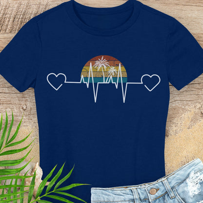 Navy blue t-shirt with a heart rate design featuring a sunset and palm trees on a wooden surface.