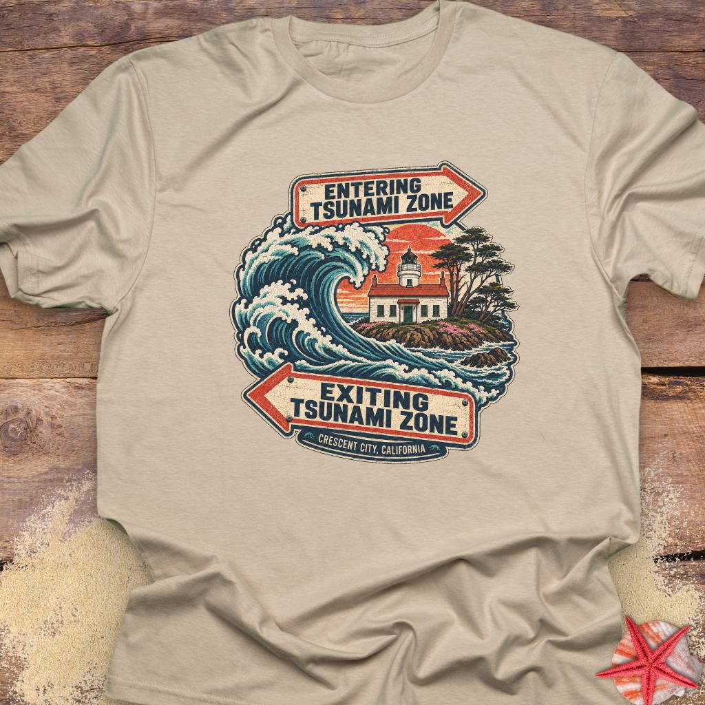 A beige crewneck t-shirt featuring a vintage-style graphic of a tsunami wave and lighthouse with arrows reading 'ENTERING TSUNAMI ZONE' and 'EXITING TSUNAMI ZONE'.