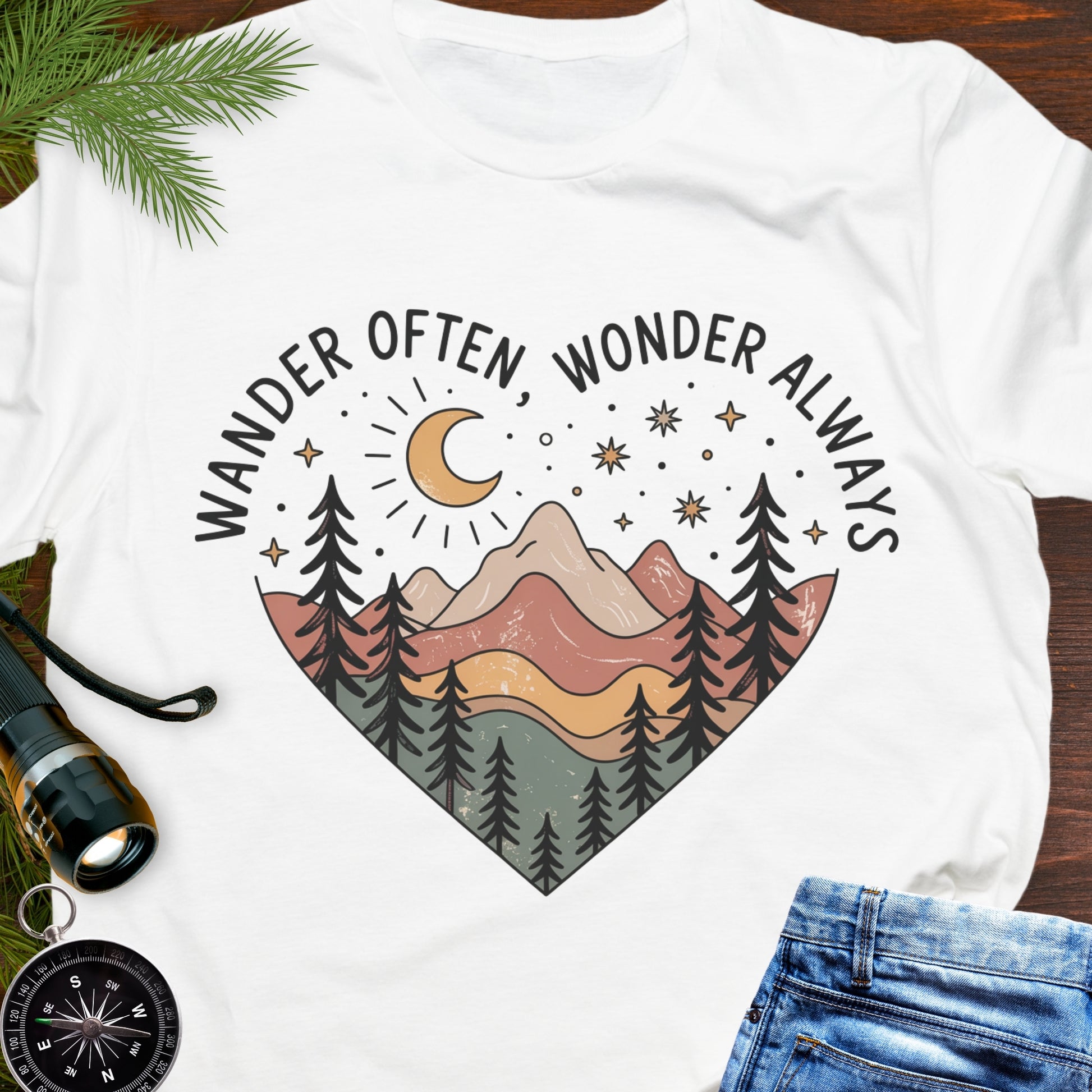 White  Unisex t-shirt with mountain and trees in a heart shape and the phrase "Wander Often, Wonder Always".