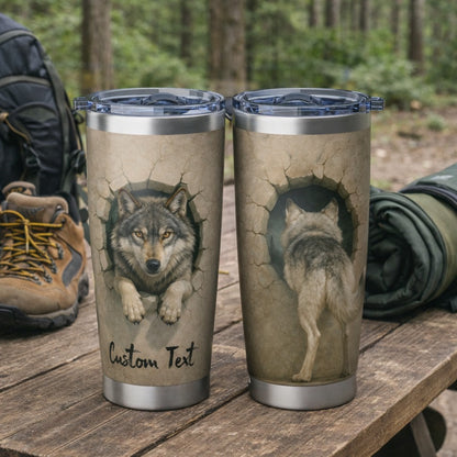 Two tumblers with wolf designs on a wooden surface in a forest setting.