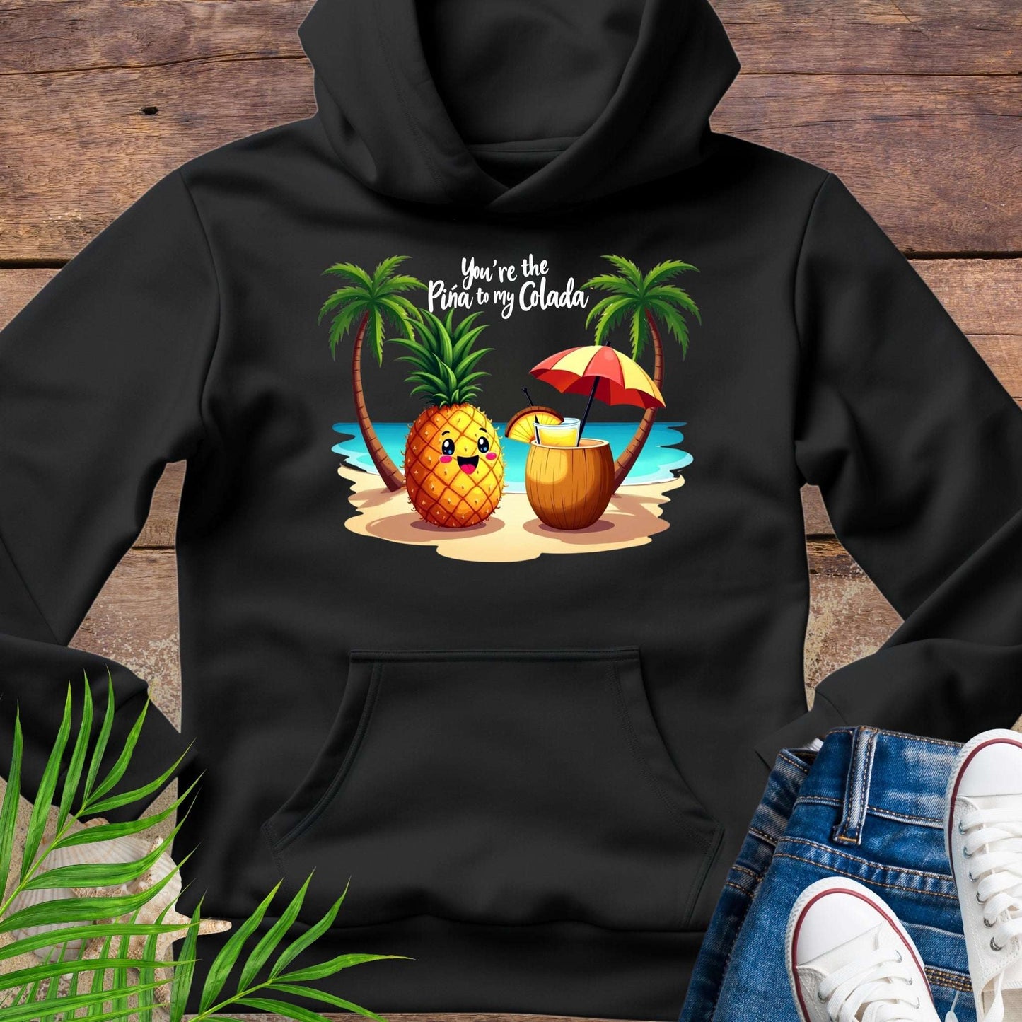 Black Hoodie with a pineapple and a coconut pina colada on a beach between two palm trees with the text You're the Pina to my Colada.