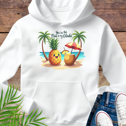 White Hoodie with a pineapple and a coconut pina colada on a beach between two palm trees with the text You're the Pina to my Colada.